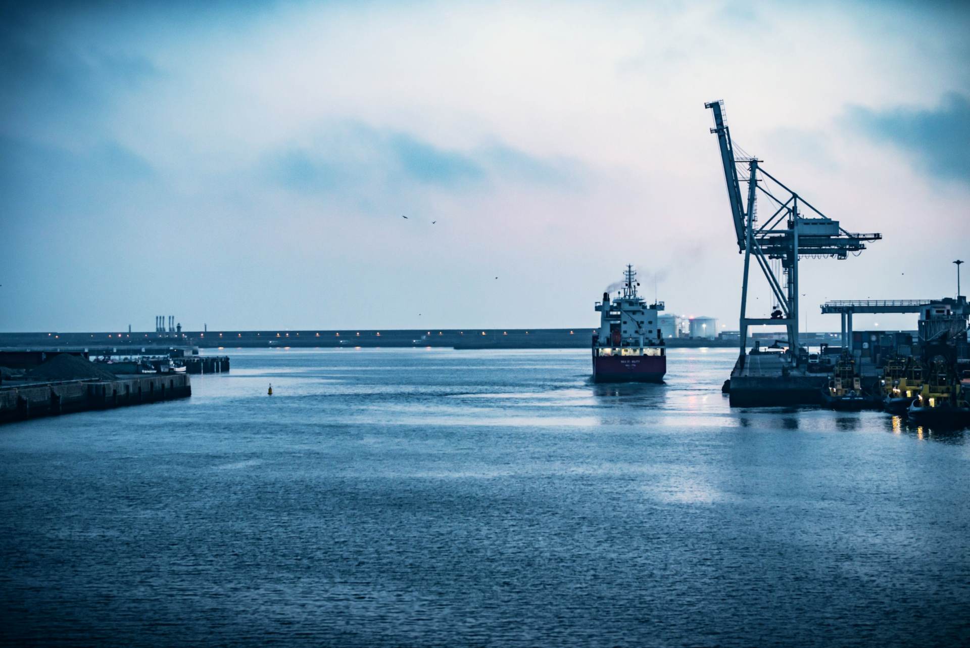 Cranes and moored vessels at a working waterfront.